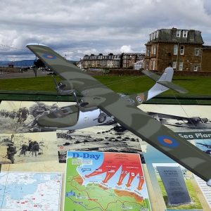 Model PBY Catalina flying boat flies above panel installation of Largs D-Day Connection