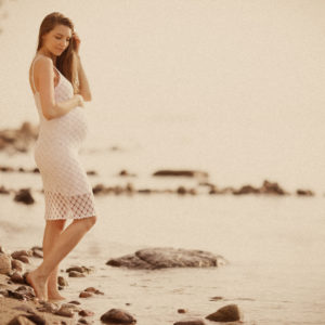 beautiful pregnant woman on the beach paddling in the sea